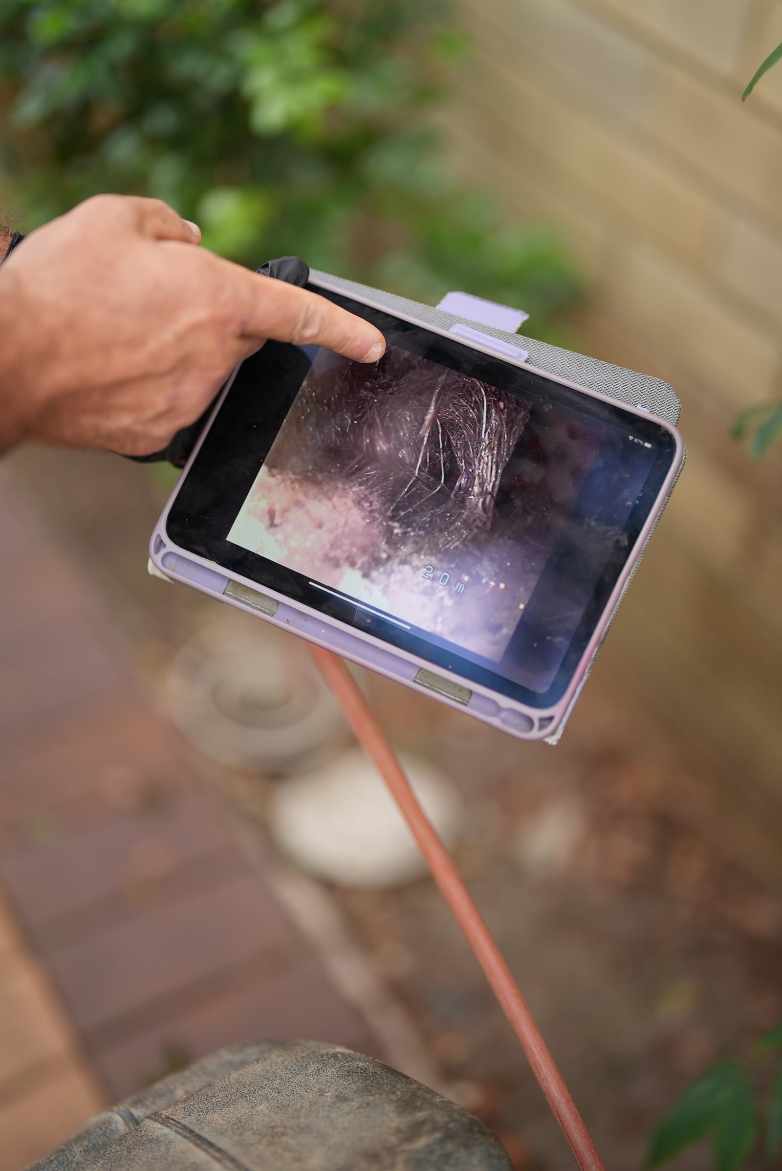 Live CCTV drain inspection footage of tree root intrusion shown on a tablet at a Sydney property